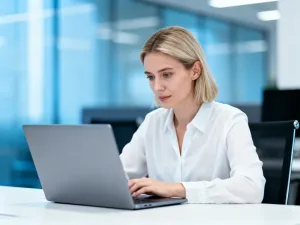 Mężczyzna pracujący przy laptopie w jasnym, minimalistycznym biurze domowym podczas logowania do systemu.